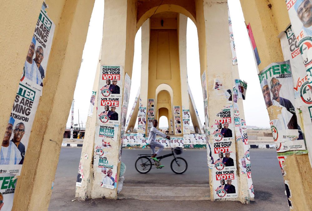 A boy rides a bicycle past a monument decorated ...