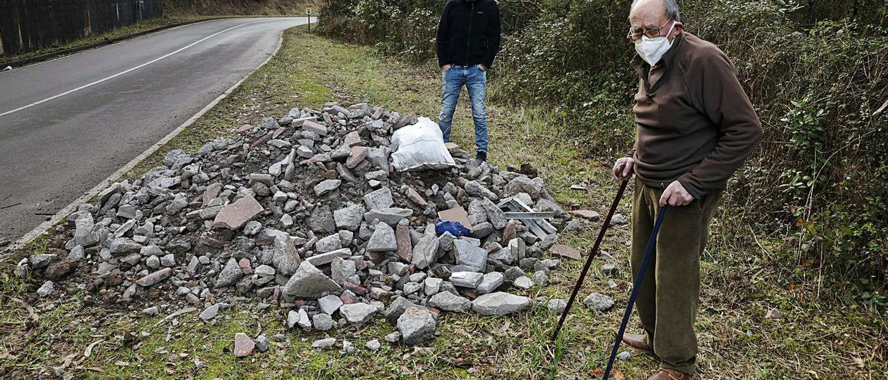 Arriba, José Luis Fernández y Luis Junquera, ante escombros de obras tiradas a pie de carretera en Serín.