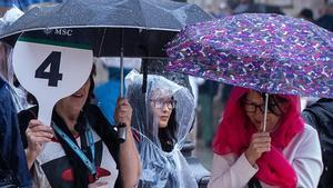 Un grupo de turistas se protegen de la lluvia en la plaza de la Virgen de Valencia.