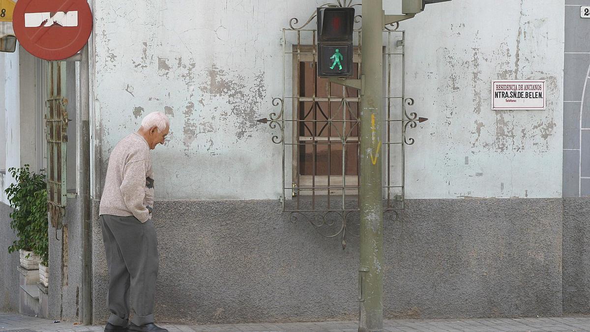 Un pensionista camina hacia un paso de peatones para cruzar la calle.