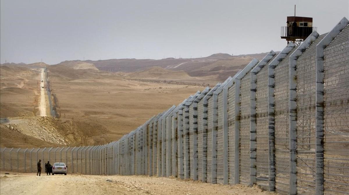 Guardias egipcios (derecha) observan desde una torre de vigilancia cómo sus homólogos israelís supervisan la construcción de una valla fronteriza entre Israel y Egipto, cerca de Eliat, el 15 de febrero del 2012.