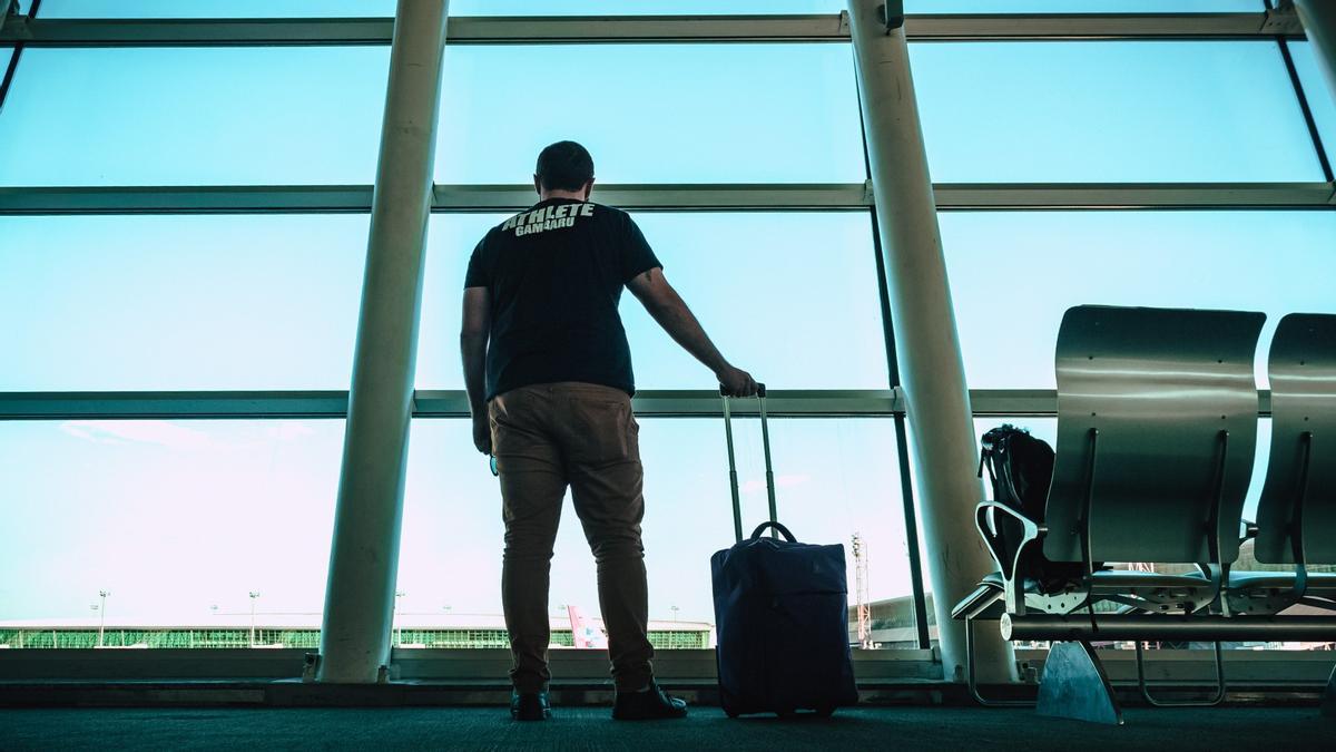 Una persona en el aeropuerto con su maleta de cabina