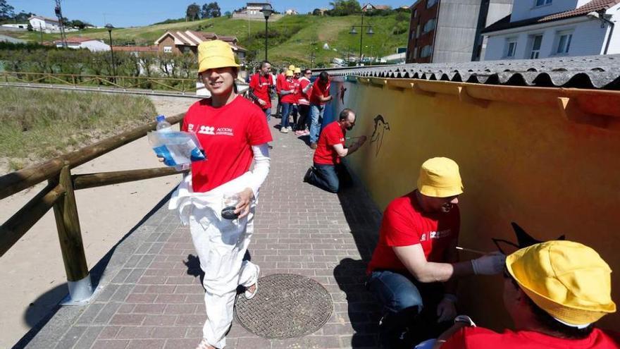 Los voluntarios de la Fundación Alcoa pintan el mural.