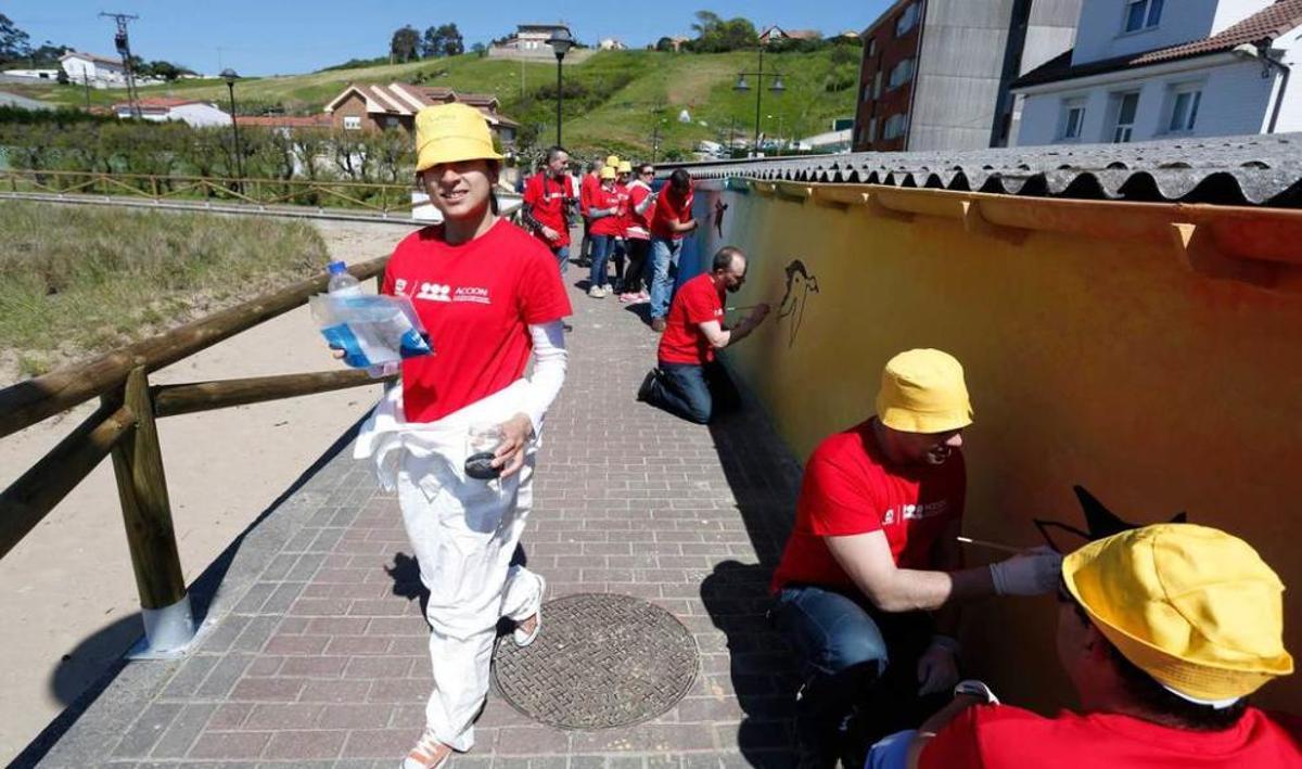 Los voluntarios de la Fundación Alcoa pintan el mural.