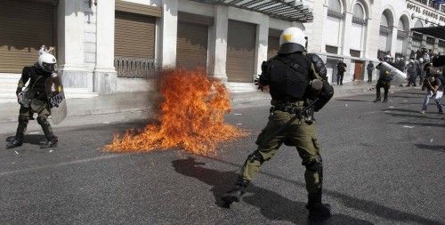 Flames from a molotov cocktail flare up near Greek riot police at a protest march by Greece's Communist party in central Athens during a 24-hour labour strike