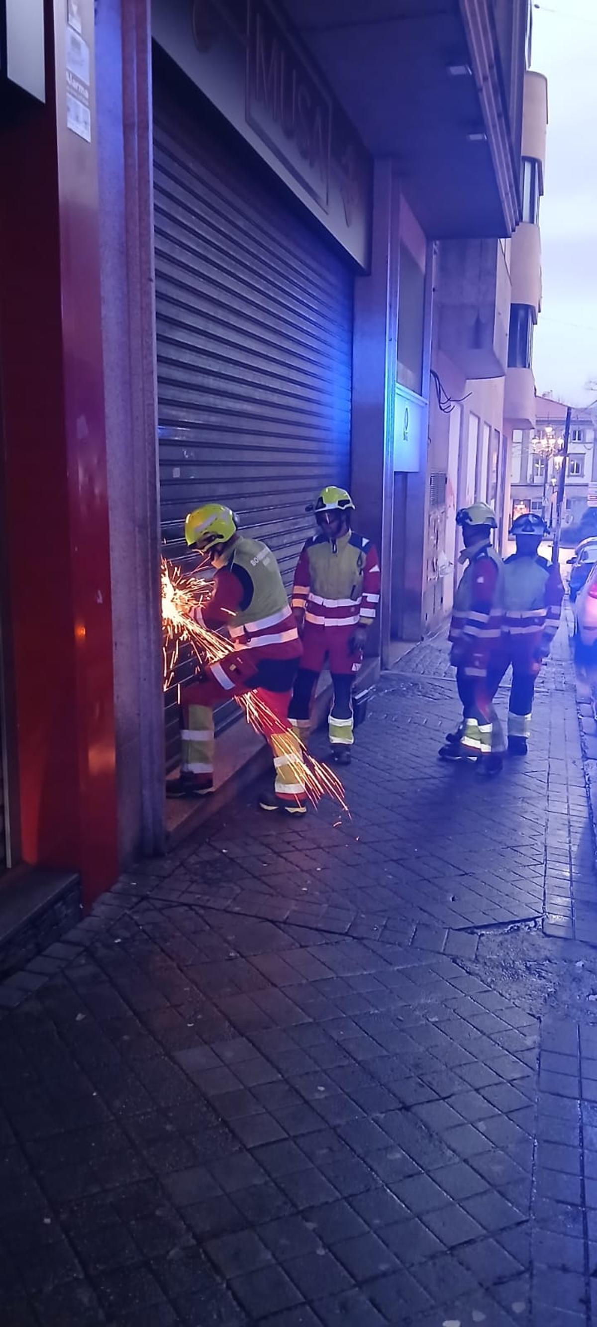 Los bomberos cortan la persiana de una discoteca para liberar a una mujer que se quedó en su interior.