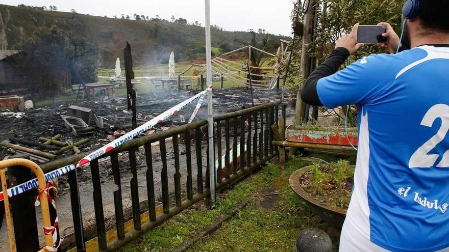 Un hombre fotografía los restos calcinados del chiringuito al día siguiente del incendio que lo asoló.