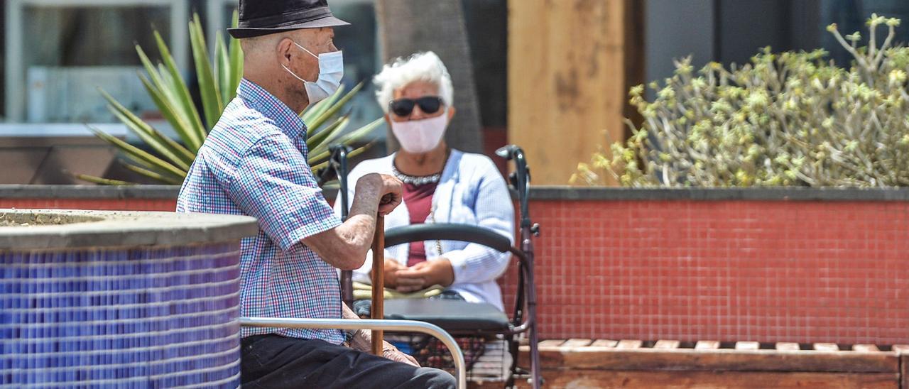 Dos personas mayores con mascarillas, en el Paseo de Las Canteras.