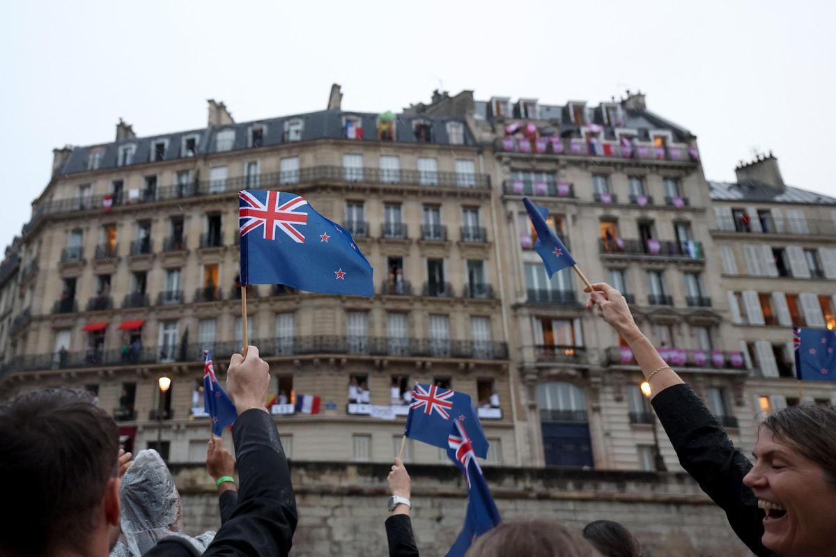Los atletas de Nueva Zelanda ondean banderas a lo largo del río Sena durante la ceremonia de apertura de los Juegos Olímpicos de París 2024