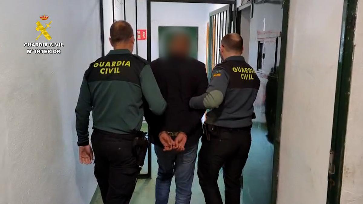 Dos guardias civiles escoltan esposado al sospechoso.