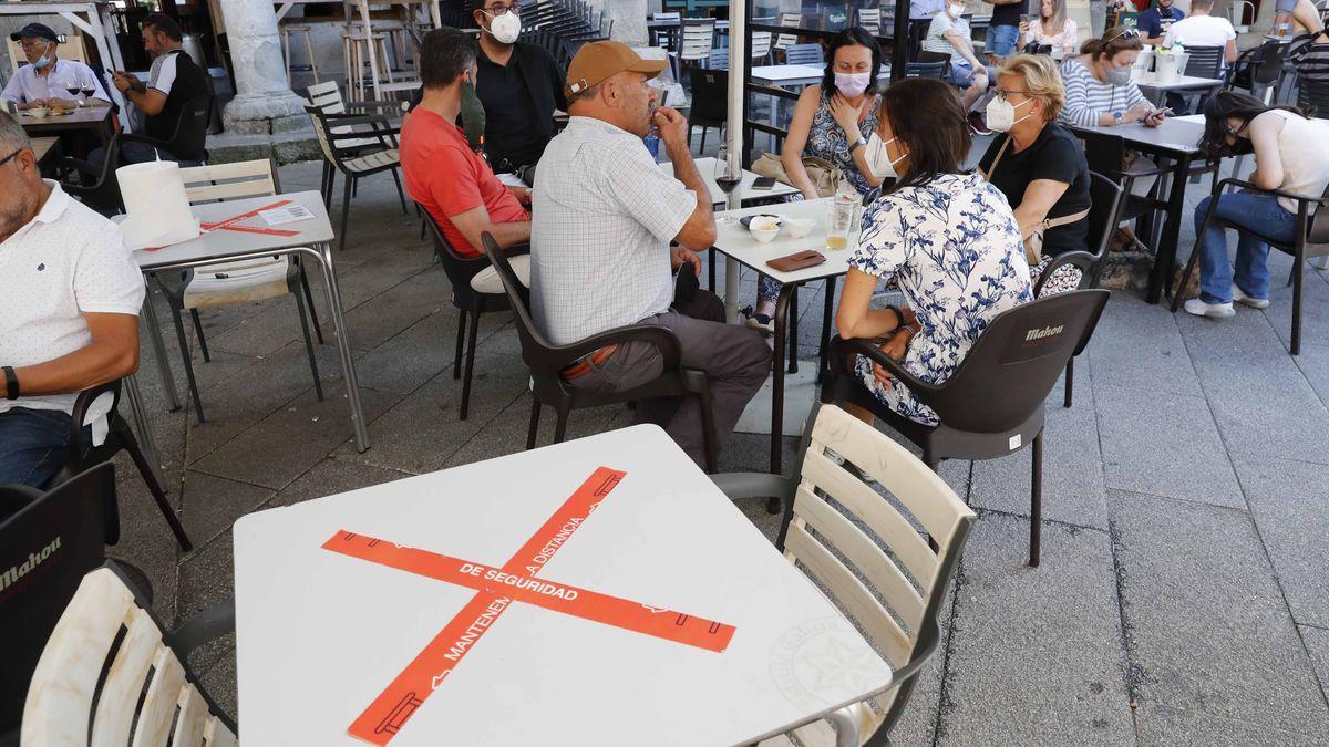 Clientes de una terraza de Vigo junto a una mesa de uso prohibido por las limitaciones de aforo.