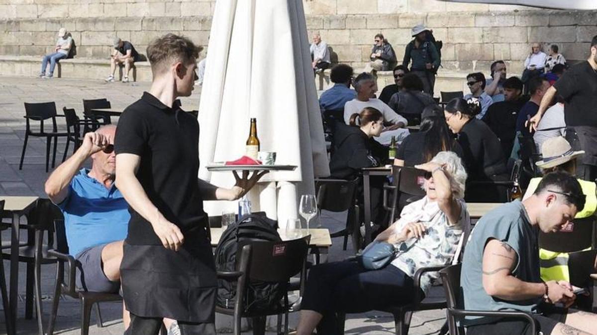 Un camarero atiende las mesas de una terraza en la Praza da Quintana, en Santiago