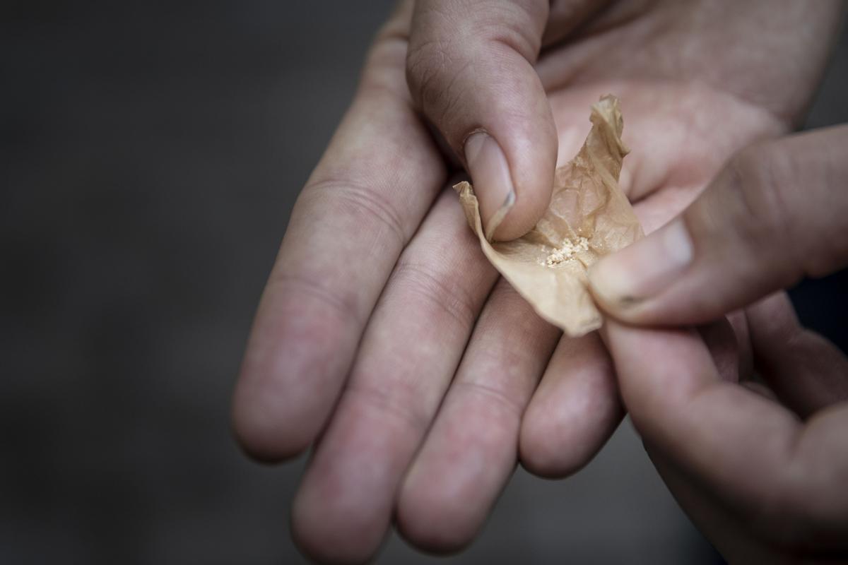 Un agente de la Guardia Urbana muestra una papelina con droga tras incautarla en el Raval.