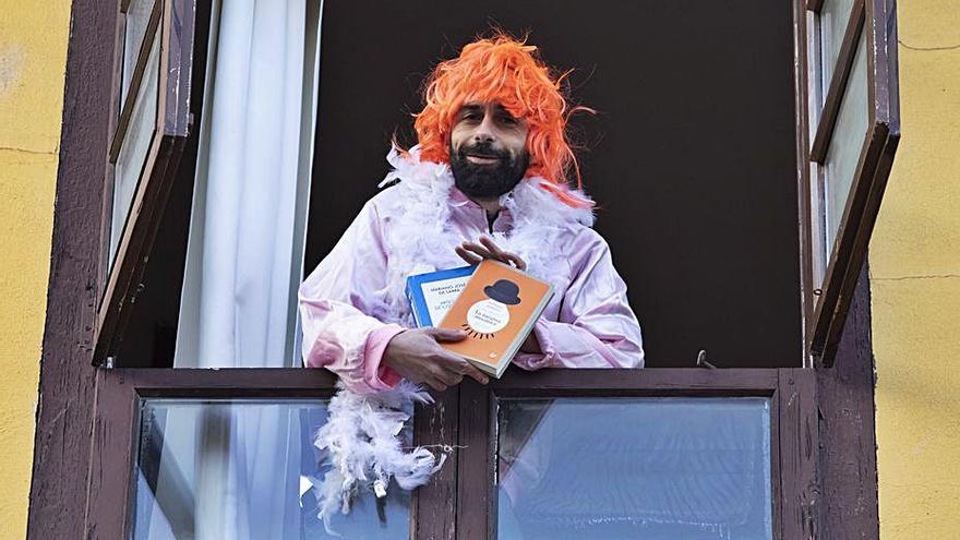 David García posa desde su ventana con peluca, boa y dos libros. | R. Solís