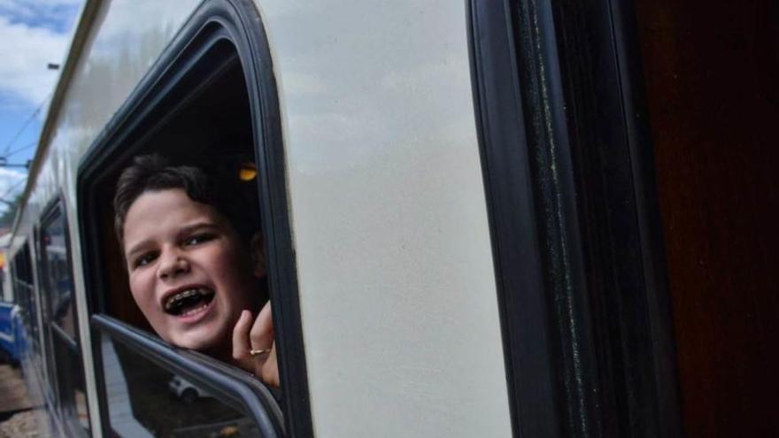 El tren, mano a mano con los primeros palistas. Jaime, un niño estadounidense que ayer acudió al Sella por primera vez, asomándose al tren fluvial.