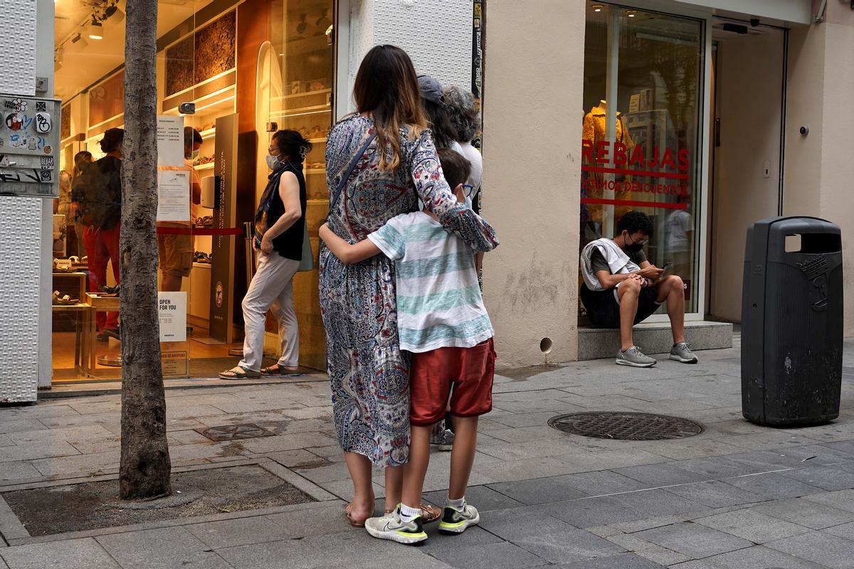 Importado de EEUU, la hiperpaternidad es un fenómeno que implica la sobreprotección de los hijos, en la imagen un niño abraza a su madre a la espera de entrar a un comercio en la calle Fuencarral en Madrid.