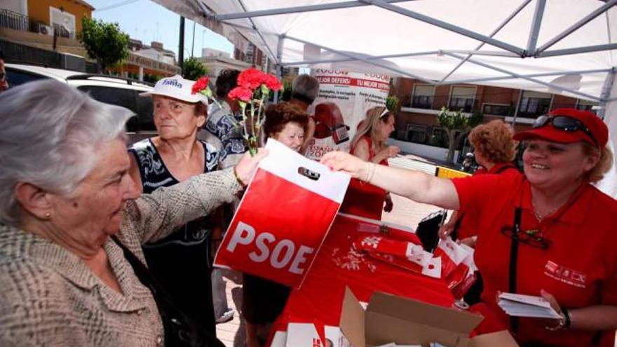 Afines a PSOE y PP repartiendo regalos, claveles, programas y votos en el acceso al mercadillo. Abajo, Navarro en el tenderete de Gema Amor y la líder de UPyD, con un vecino.