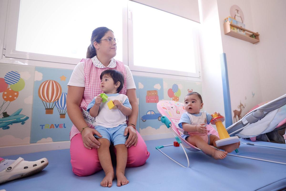 Una profesora junto a dos menores en una escuela infanti.