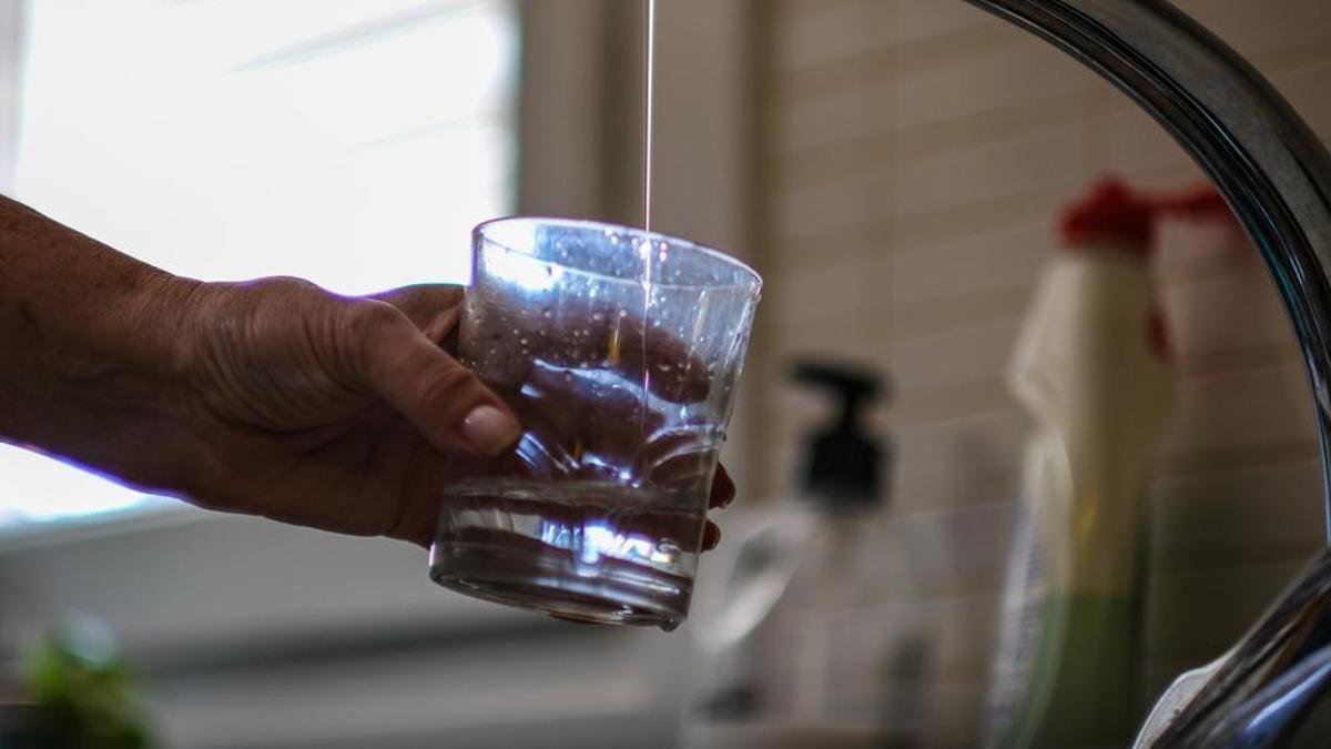 Una mujer trata de llenar un vaso con el hilo de agua que sale del grifo, en una imagen de archivo.