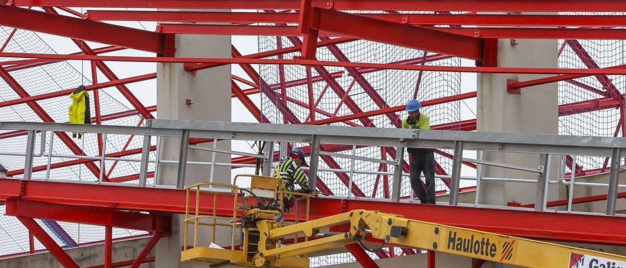 Dos operarios de Eiffage trabajando ayer en la colocación de la cubierta en la futura nave cerrada  para los graneles del puerto. | HÉCTOR FUENTES