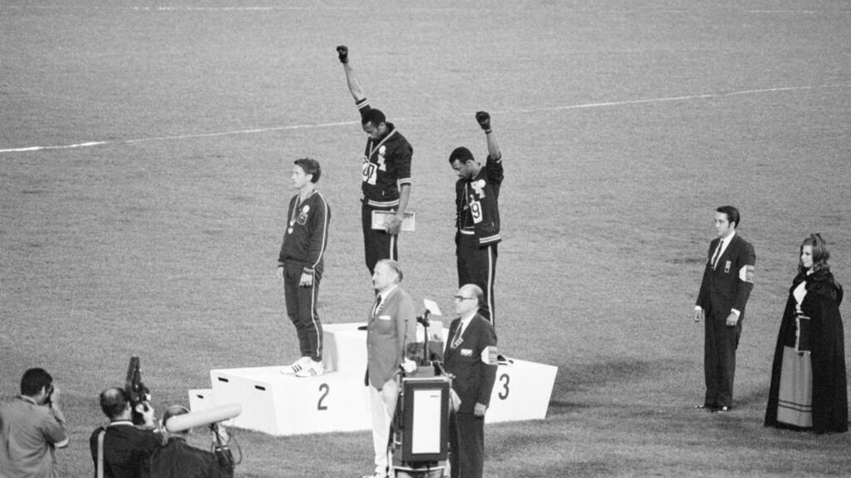 Tommie Smith y John Carlos, atletas estadounidenses, levantan el puño como gesto contra el racismo en el podio olímpico.
