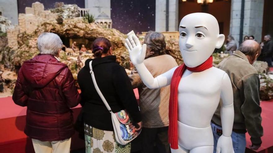 Un maniquí del anuncio de este año de la Lotería saluda ante un belén.