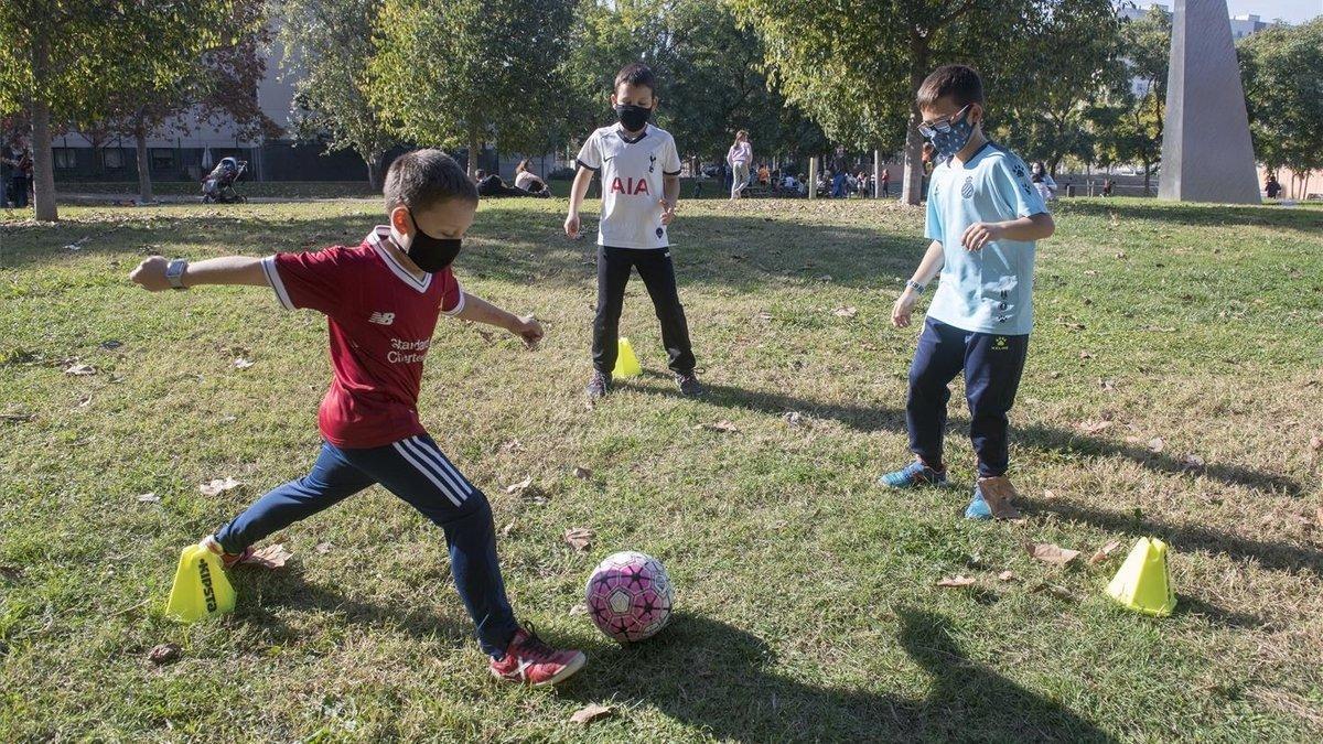 Iván (de rojo) y su hermano Iago (de blanco) se entrenan un parque de Cornellà junto a Víctor, también de la UE Cornellà.