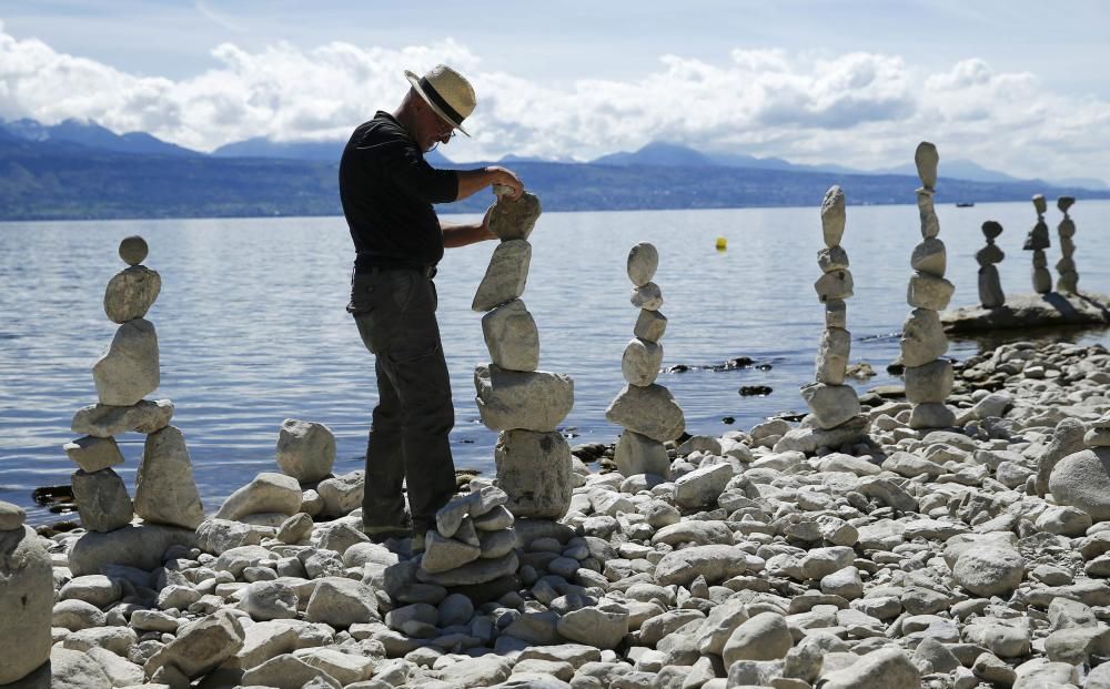 El artista suizo Daniel Dunken pone en pie un montón de piedras en la orilla del lago Leman, en Lutry, Suiza.