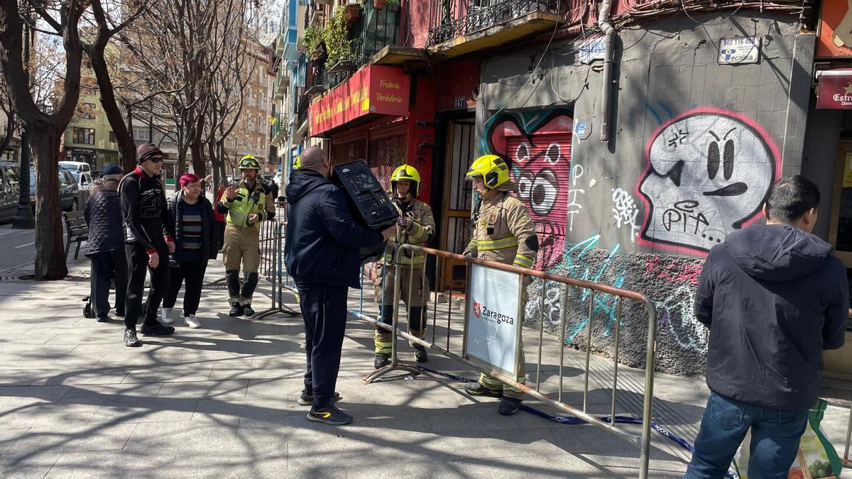 Un vecino, este jueves, recibe de manos de los bomberos las pertenencias que pudieron sacar de su piso.