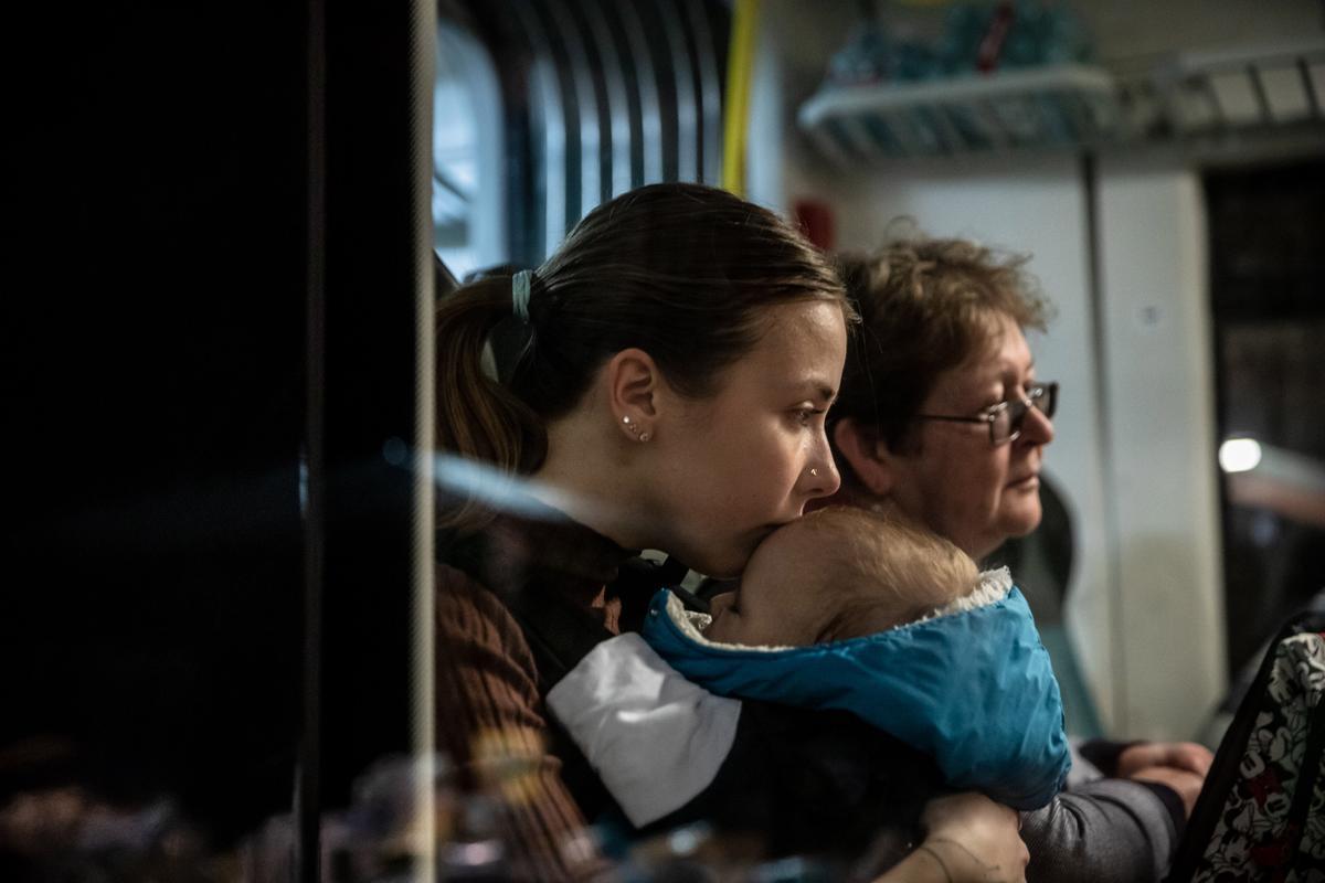 Una refugiada ucraniana abraza a su bebé, dormido, mientras espera la salida de su tren en la estación de Przemysl, en Polonia.