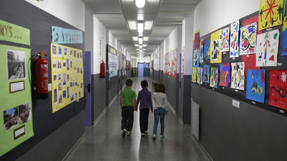 Tres alumnos en el pasillo vacío del colegio Joan Miró, este martes, en Barcelona.