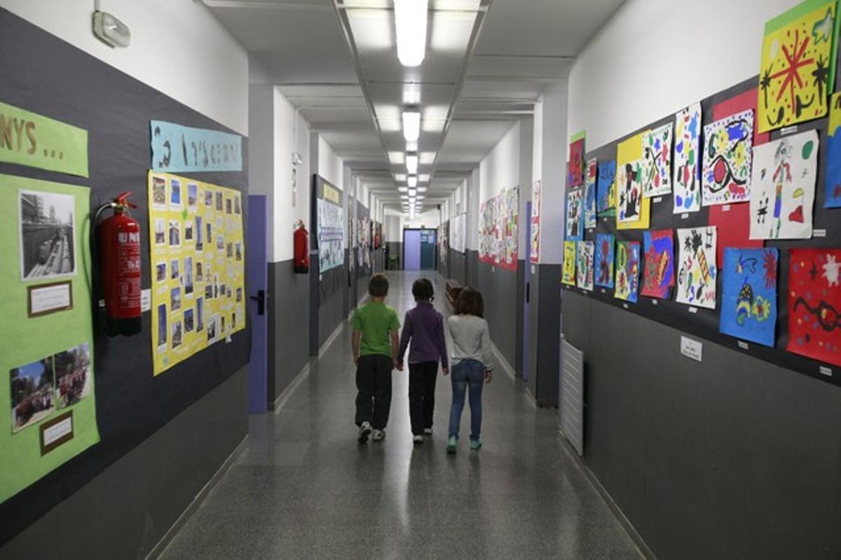 Tres alumnos en el pasillo vacío del colegio Joan Miró, este martes, en Barcelona.