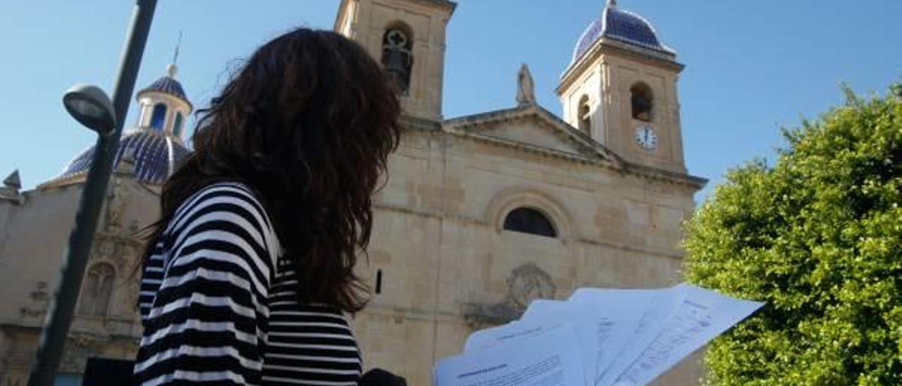 María Teresa muestra las firmas de apoyo recogidas, ante los dos campanarios de la parroquia de Sant Joan.