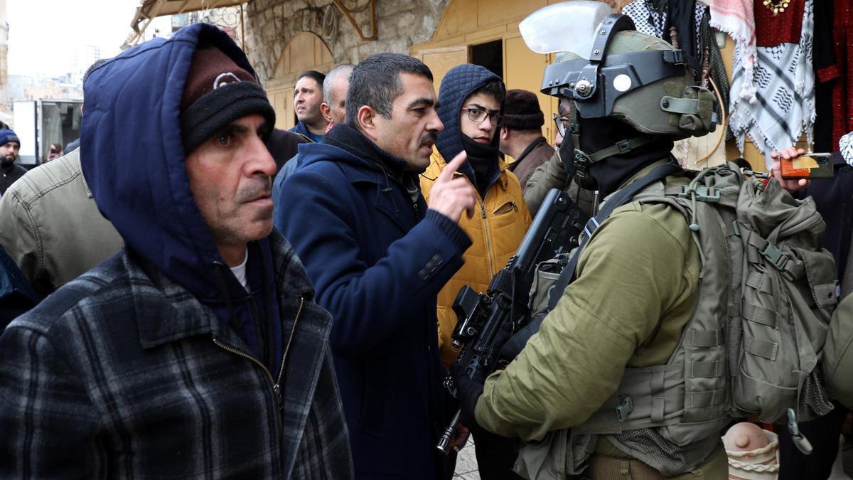 Un soldado israelí impidiendo a unos comerciantes palestinos abrir sus tiendas en Hebrón.
