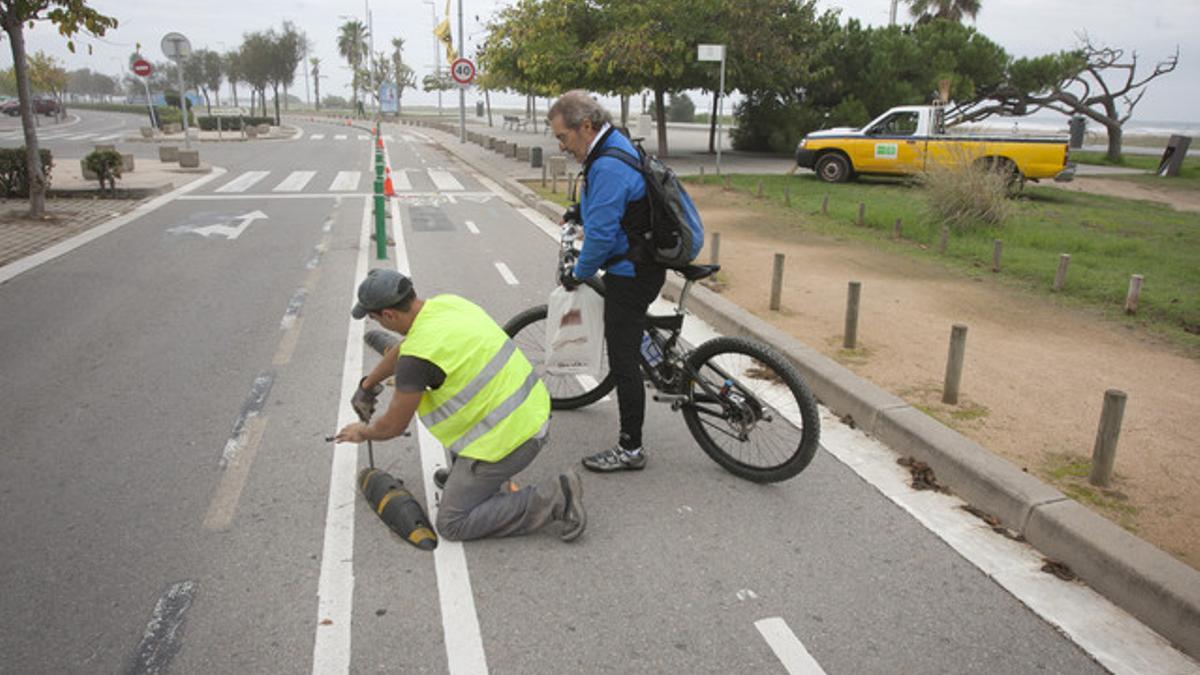 Un operario desmonta los separadores del carril bici en Castelldefels ante la presencia de un ciclista.