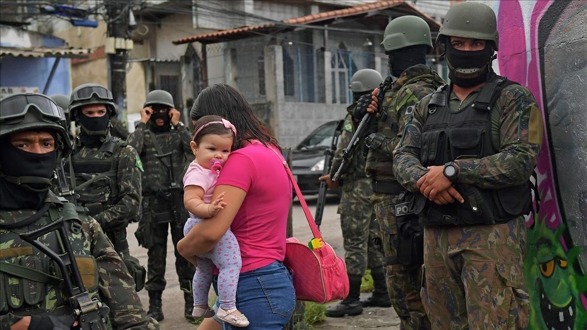 zentauroepp42286599 a woman carries her child as she walks past military police 201020133000