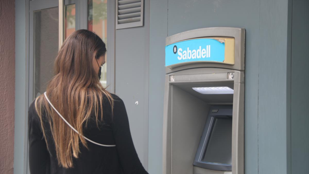 Una clienta del Banc Sabadell retirant efectiu d&#039;un caixer situat a una oficina de Barcelona