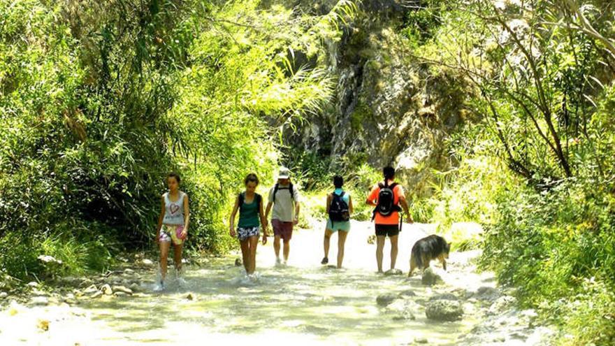 Un grupo de senderistas cruzan el río Chíllar en pleno mes de julio.