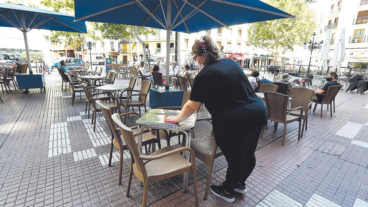 Una camarera limpia una mesa en la Plaza del Carmen de Zaragoza