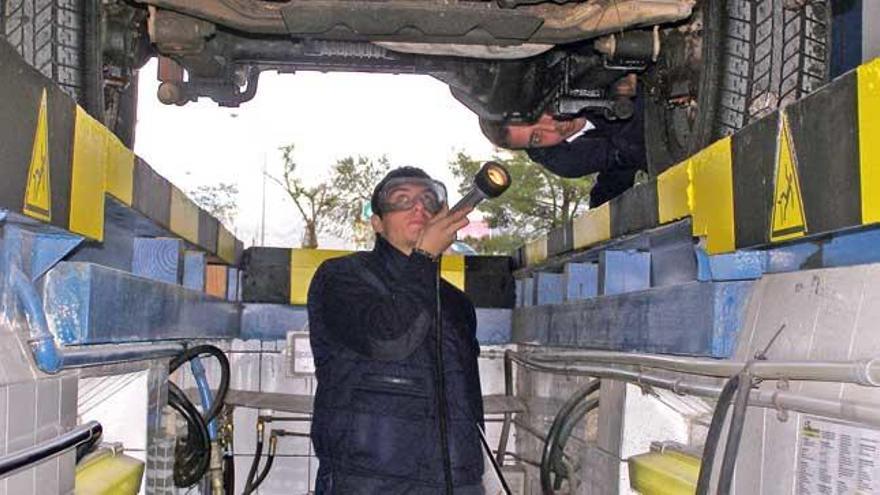 Un operario inspecciona los bajos de un vehículo, durante una revisión de la ITV.