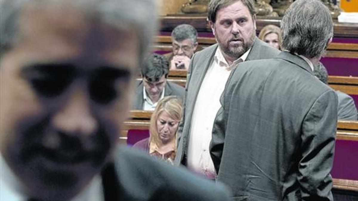 Junqueras y Mas se cruzan a espaldas de Francesc Homs, en primer plano, el pasado viernes en el Parlament.