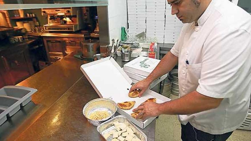 Un empleado de la pizzería Chicote traslada parte de un plato a uno de sus &quot;tuppers&quot;.  // J. de Arcos