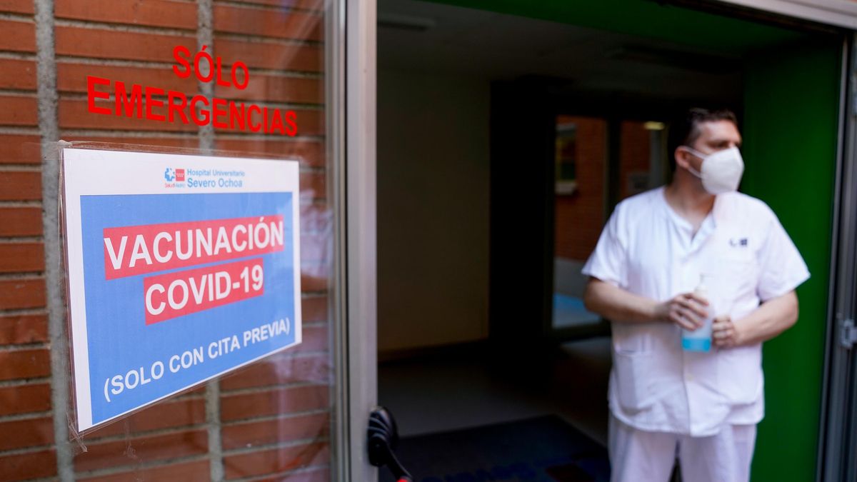 Un empleado sanitario al lado de una señal del dispositivo de vacunación.