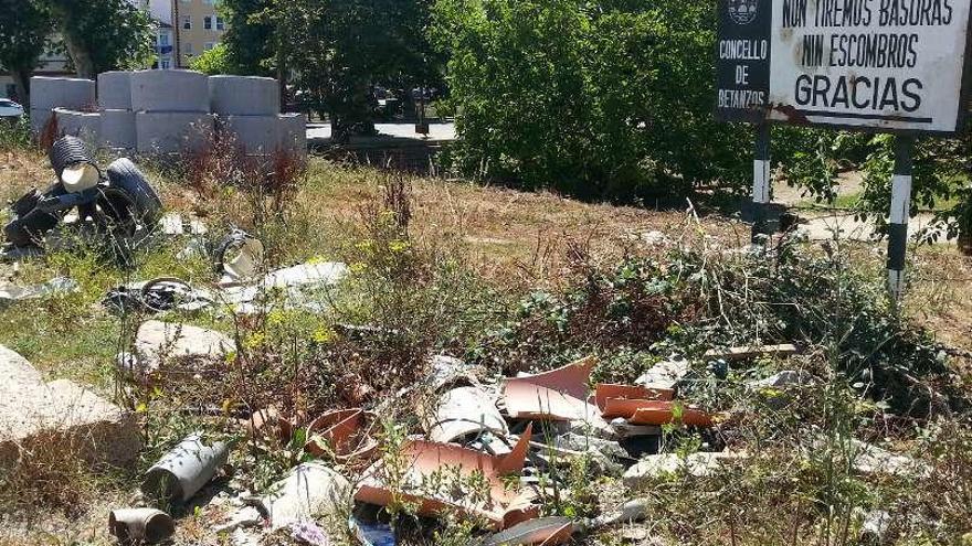 Basura y escombros se acumulan junto a un cartel que insta a no tirar residuos