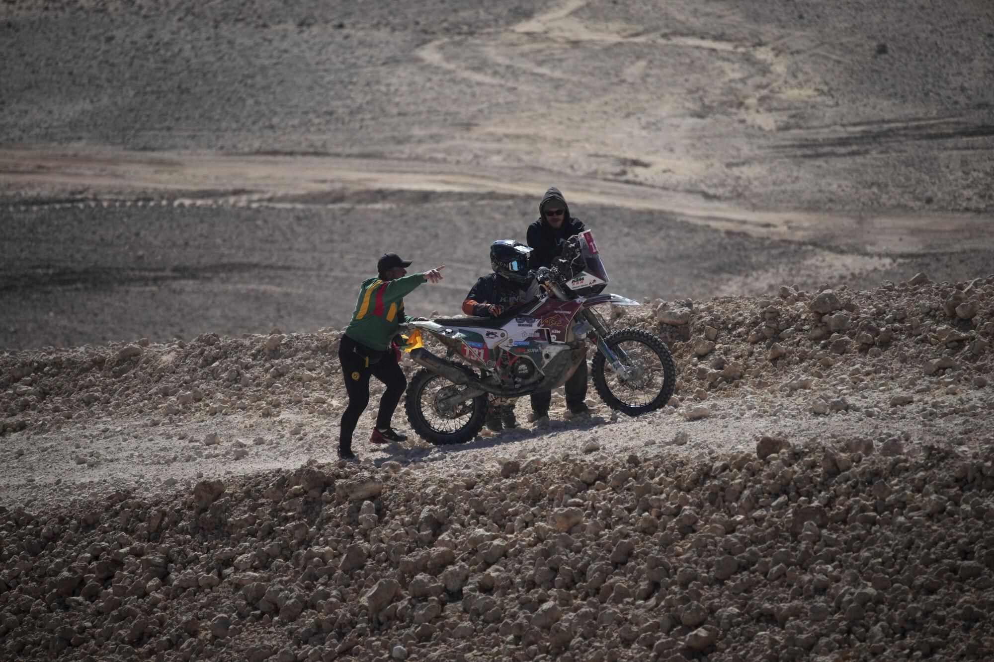 Rider Ahmed Aljaber is helped by spectators after falling during the ninth stage of the Dakar Rally between Riyadh and Haradh, Saudi Arabia, Tuesday, Jan. 14, 2025. (AP Photo/Christophe Ena)