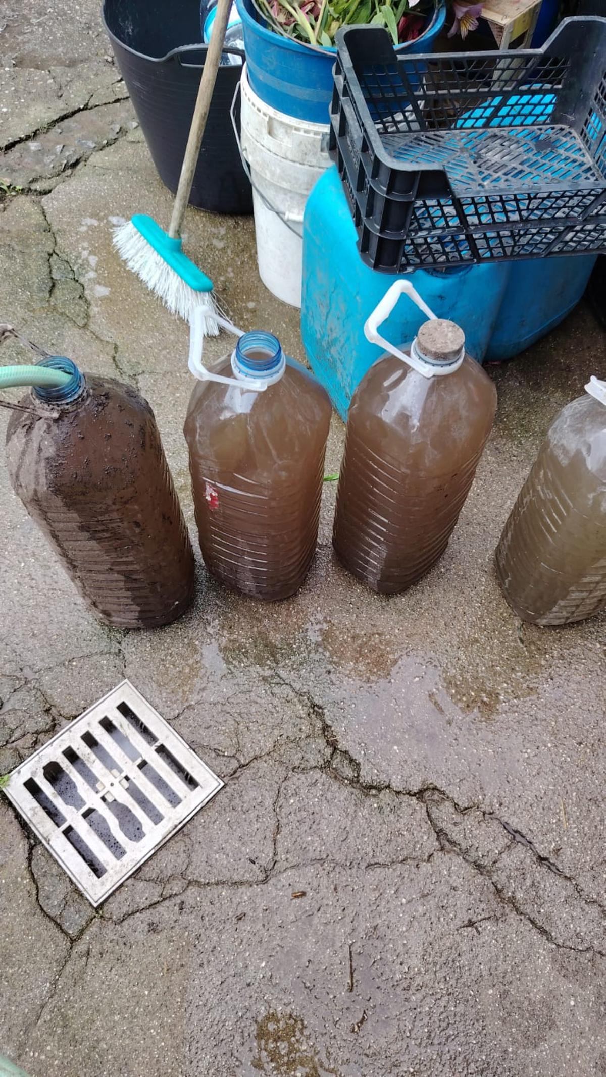 Una imagen aportada por vecinos, con varias garrafas llenas de agua turbia durante la mañana del jueves 14 de mayo.