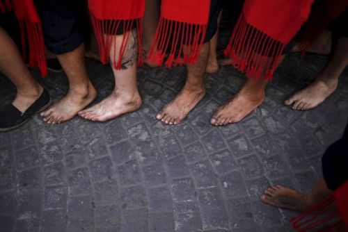 The feet of men in traditional costumes are seen as they carry a statue of the El Carmen Virgin on its way into the sea during a procession in Malaga