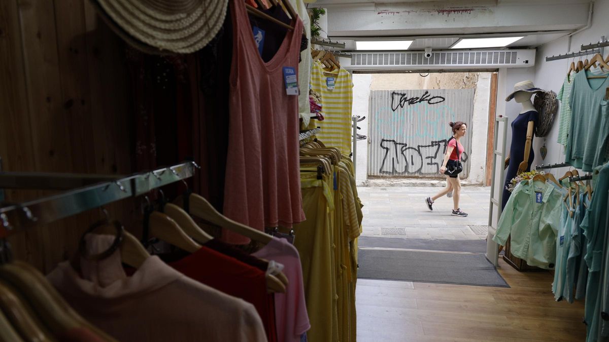 Una joven pasa por la puerta de una tienda de ropa del centro de Cartagena, este lunes por la mañana.