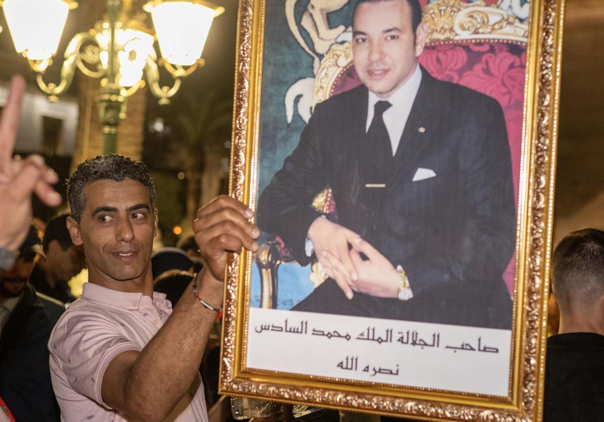 Personas celebrando la resolución de la ONU en Rabat con un cuadro de Mohamed VI.