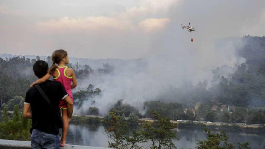 Una mujer refresca su finca, ante la proximidad del fuego en Pereiro de Aguiar. // Brais Lorenzo.